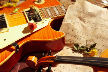 Naklejka na ściany i meble Vintage electric guitar, rare violin, dried flowers and old sheet music on wooden background close up.