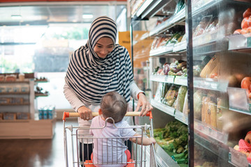 muslim asian Mother hijab and baby shopping in the supermarket. grocery store shopping
