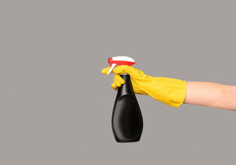 Hands in gloves for bottles spray for disinfect on grey background