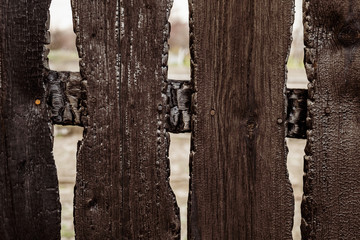 Burnt fence boards after a fire in a private house.