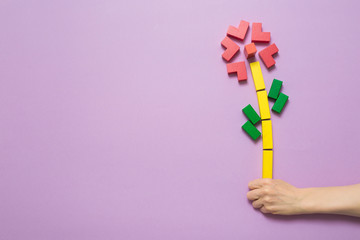 Creative gift eco flower from colored cubes in a hand. Copy space.