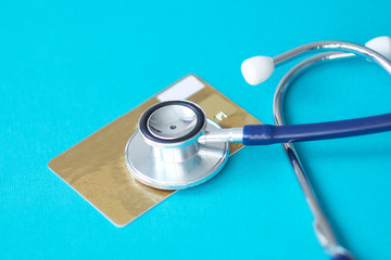 Stethoscope on Mock up Credit Card with number on cardholder in hospital desk. Health insurance and...