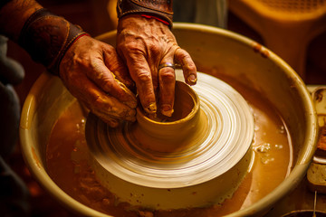 The master forms a clay cup on a potter's wheel. A potter's hands preparing a clay pot. Close-up.
