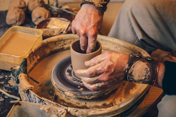 The master forms a clay cup on a potter's wheel. A potter's hands preparing a clay pot. Close-up.