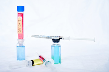 A syringe for injection with a coronavirus vaccine, antiviral tablets and 2 syringes with red and yellow liquids on a white background