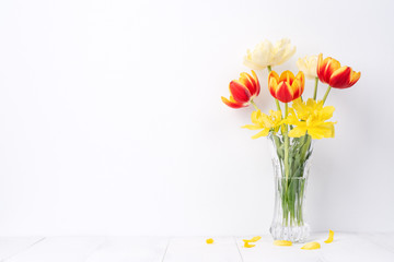Tulip flower in glass vase with picture frame place on white wooden table background against clean wall at home, close up, Mother's Day decor concept.