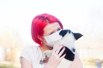 Young red hair girl wear protection mask and holding puppy outdoors. To prevent pathogens caused by sick dog. Health care with pet and natural. Covid-19 virus.