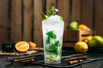 Fresh cool mojito cocktail in a highball glass on the wooden background, horisontal, side view