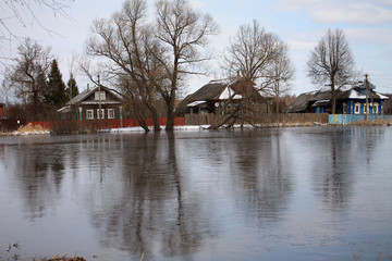 Obraz premium Houses near the water. Trees are reflected on ice.