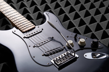 Fototapeta na wymiar black electric guitar lying on acoustic foam panel