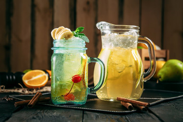 fresh yellow banana sweet lemonade in jars on the dark wooden background, horizontal, side view
