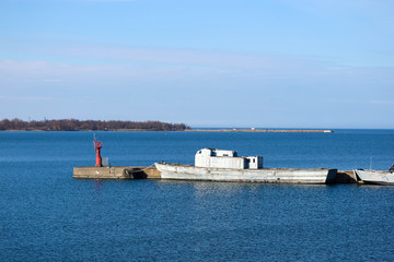 abandoned warship near the pier with the blue sea on the background