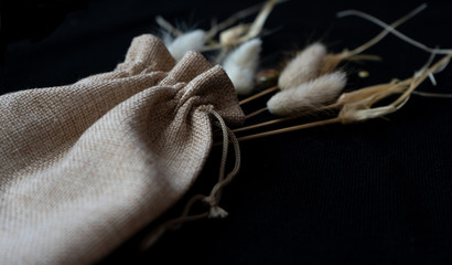 cotton light bag, twigs of dried flowers on a black background, clean ecology