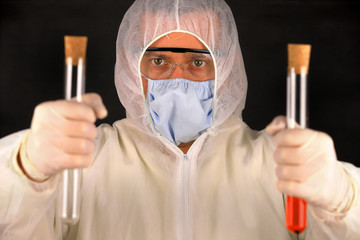 The doctor in a protective suit and mask holding a glass tube with a blood test for the new rapidly...