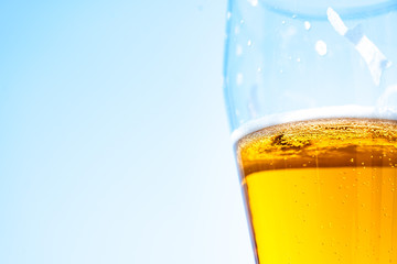Light beer in a glass goblet on a background of blue sky. Beer foam on the walls of a glass in the sunlight.