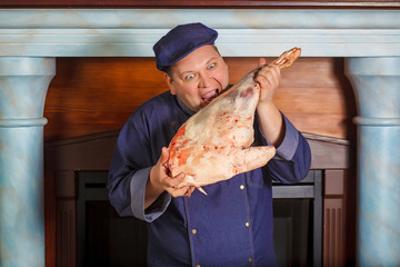 Half legth shot of thoughtful male chef, holds very big red raw piece of meat, needs to chop for...