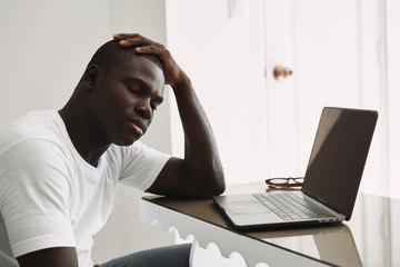 A man of African appearance at home in front of a laptop relaxing