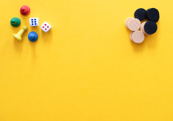 Chess pieces, game chips, Lotto barrels, draughts and playing cubes are laid on a yellow...