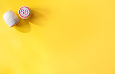 Two Lotto barrels with numbers on a yellow background, one standing and one lying: concept of Board games, entertainment, leisure, games for the whole family at home, top view