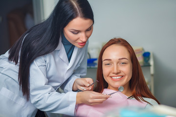 Young beautiful woman with beautiful white teeth sitting on a dental chair. Portrait of a woman with toothy smile sitting during examination at the dental office