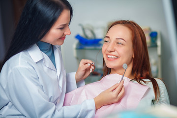 Young beautiful woman with beautiful white teeth sitting on a dental chair. Portrait of a woman with toothy smile sitting during examination at the dental office