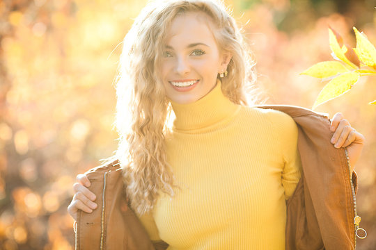 Close up portrait of beautiful blond girl on autumn background. Stylish young lady in park. Beautiful blond girl outdoors.