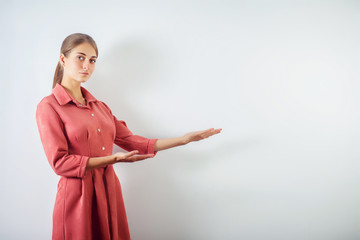Portrait of a girl in a red strict dress, shows her hand on an empty copy of the place, shows the...