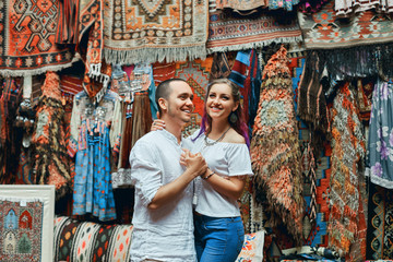 Couple in love walks and hugs at the Eastern carpet market. A man and a woman choose a Turkish carpet