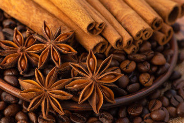 Stars of anise, coffee beans in a saucer and cinnamon sticks close - up in brown tones.