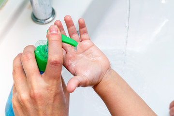 kid, child hands treatment with soap and sanitizer disinfectants from dispenser close up