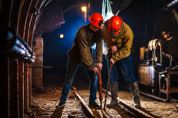 Miners in the process of working with tools in their hands. Coal mine. Two miners in the mine. Copy Space