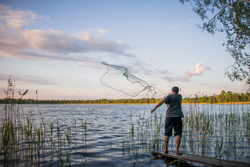 fisherman throws a net into the lake
