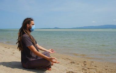 Fototapeta na wymiar COVID-19 epidemic, a man in a surgical mask meditates, keep calm and hygiene