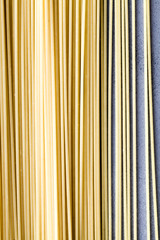 Yellow long spaghetti on blue background. Raw spaghetti bolognese.