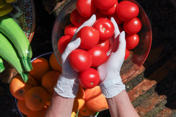 Imagen de tomates frescos rojos orgánicos con guantes blancos sanitarios para proteger los alimentos de cualquier tipo de bacteria o virus