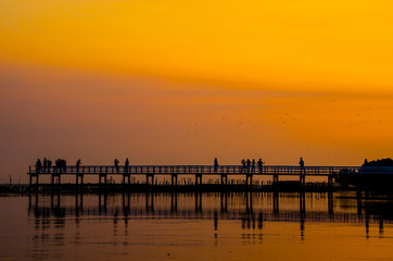 Fototapeta na wymiar Wooden bridge and people against the sunset sky background