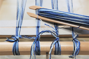 Tying knots, Wood weaving shuttle with blue and white wool warped around it, weaving loom vintage...