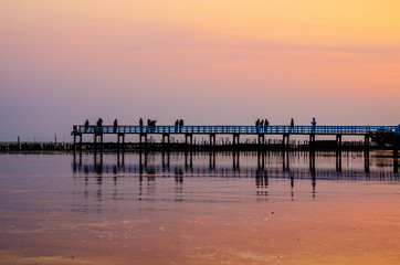 Fototapeta na wymiar People walking on a wooden bridge against the sunset sky background, silhouette image