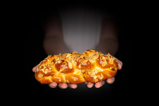 Traditional Czech Christmas cake, Vanocka, delicious breakfast for whole family full of nuts and almonds on black background holding by a man.