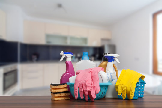 Home cleaning service concept with supplies. Close up of cleaning supplies in front of kitchen.