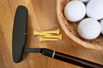 Golf club, golf balls and some tees on parquet floor