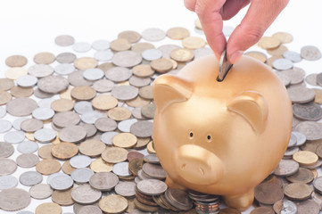 Inserting a coin into a gold piggy bank. Making savings concept