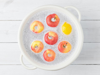 Washing apples in a cup with foam after purchase, top view. Wash fruits after purchase to eliminate viruses, infections, and dirt.