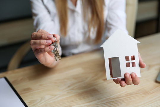concept of buing house. Realtor's hands holding house keys and house model. conclusion of a transaction for the purchase of real estate. getting housing keys close-up. expansion of living space