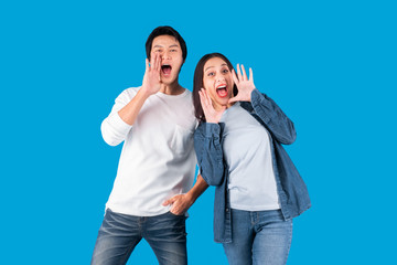 Obraz premium Asian couple man and woman shout and announce with loud over blue background with copy space
