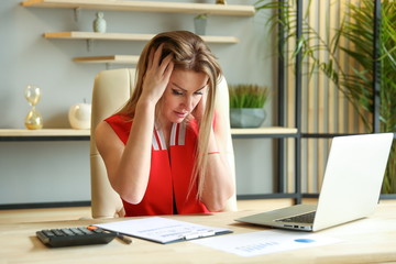 conceptual photo of the financial crisis. reporting does not converge. woman in office in despair holding her head. trouble at work. 