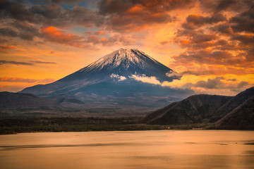 Landscape image of Mt. Fuji over Lake Motosu with autumn foliage at sunset in Yamanashi, Japan.