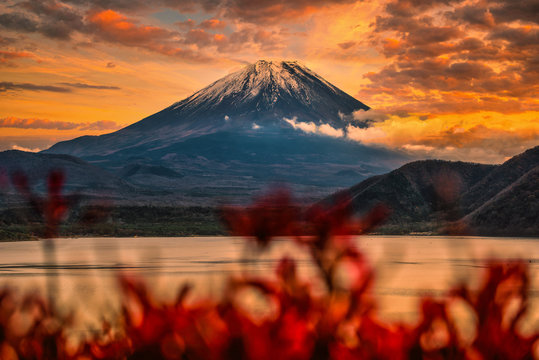 Landscape image of Mt. Fuji over Lake Motosu with autumn foliage at sunset in Yamanashi, Japan.