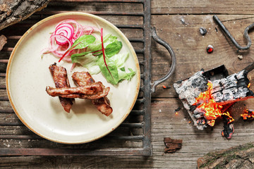 lunch grilled meat pork on vintage wood table in rustic style. Coals in the fire flame. BBC food.