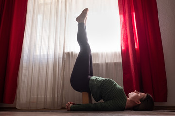 Young woman practicing yoga, doing Viparita Karani exercise, upside down pose